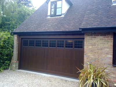 Timber Sectional Garage Door fully finished in dark oak with diamond lead windows